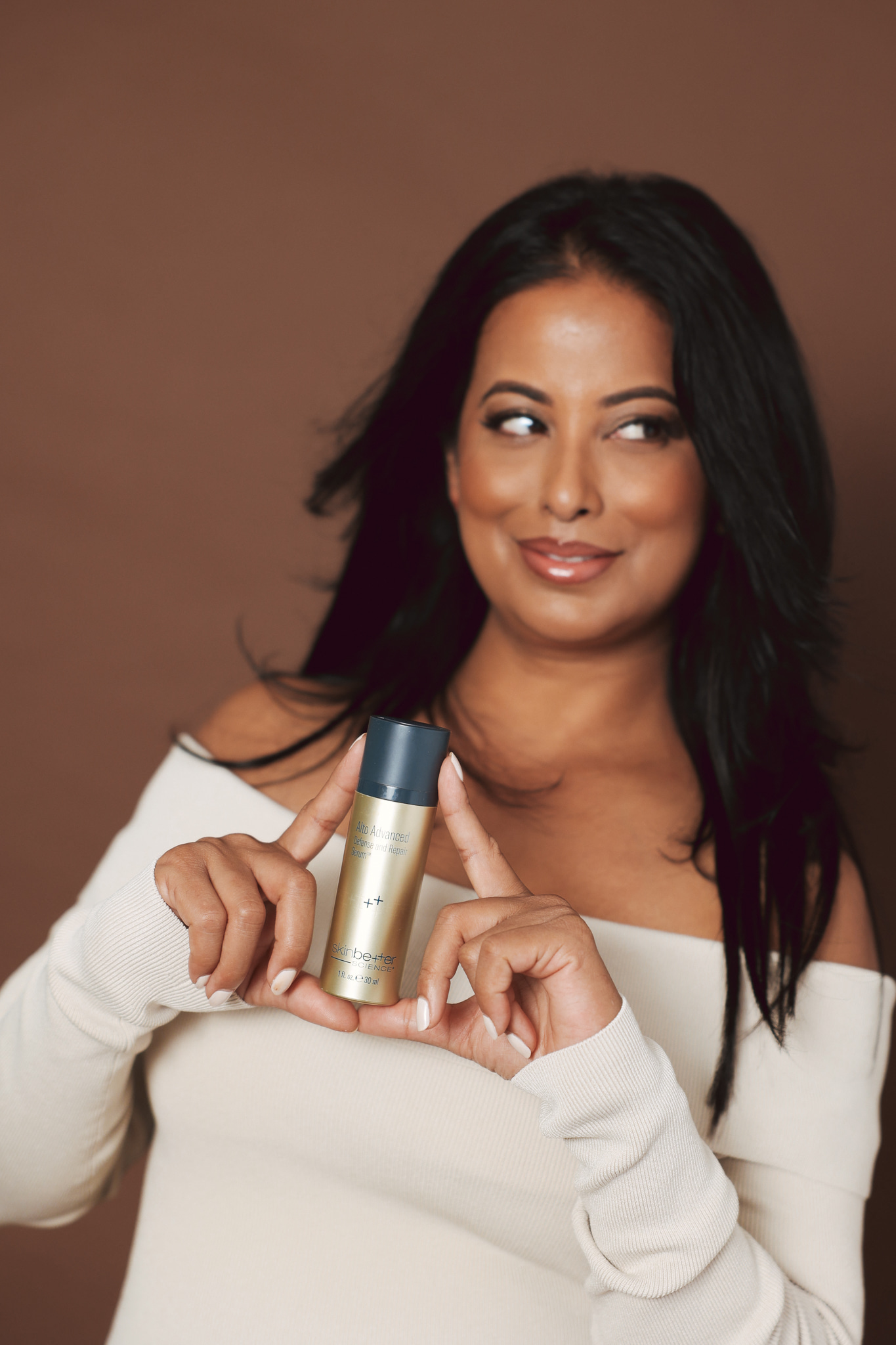 Roshani Patel smiling and holding a SkinBetter Science serum